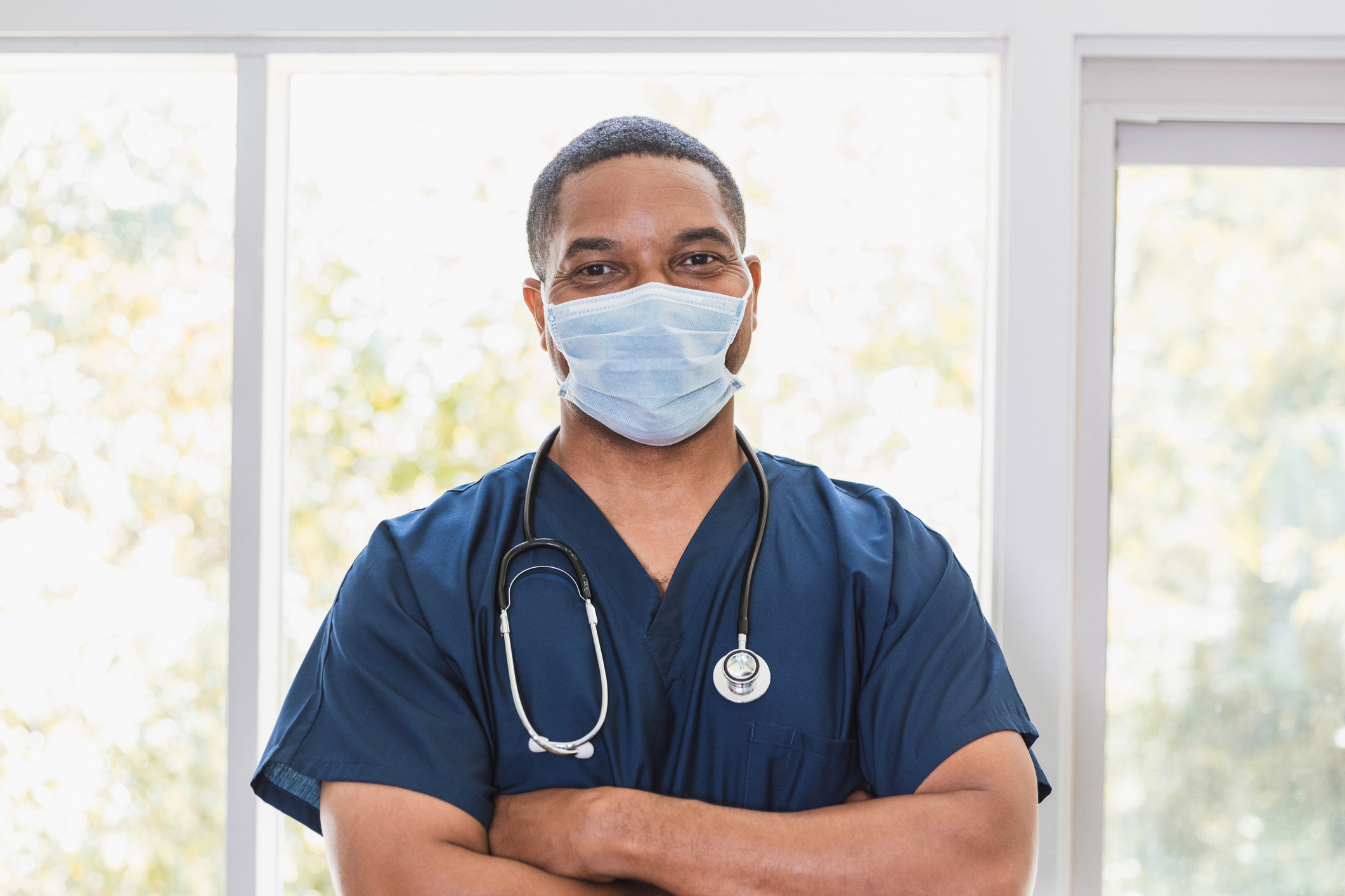 Male nurse wearing mask looks at the camera with his arms crossed. 